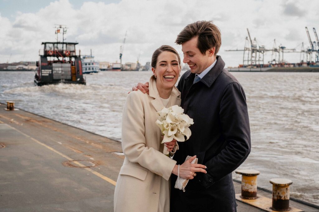 Ein Brautpaar posiert vor dem Hamburger Hafen für die Kamera.