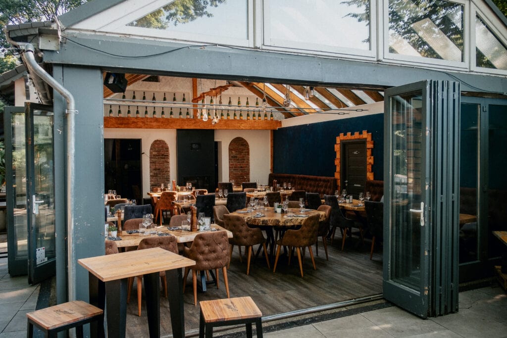 Durch eine geöffnete Tür lässt sich in den Glaspavillon des Restaurants Eppendorfer Insel blicken, wo bereits Tische für eine Hochzeitsfeier gedeckt sind.