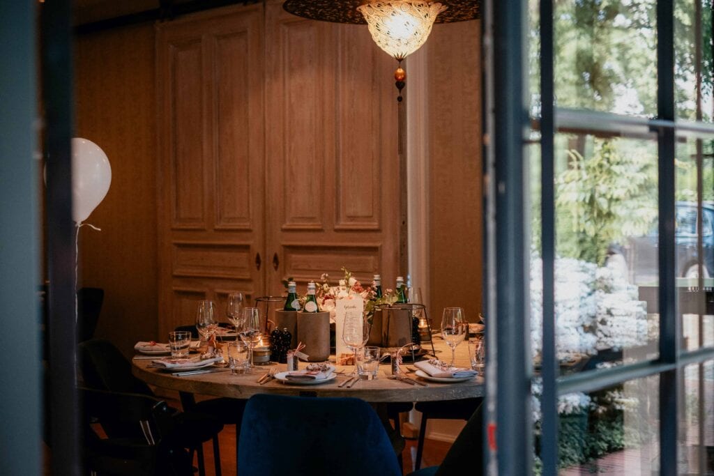 Durch eine offene Tür ist ein für die Hochzeitsfeier gedeckter Tisch in der Pulvermühle Hamburg zu sehen.